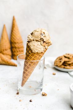 an ice cream cone with cookies on the side and in a glass next to it