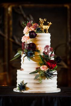 a wedding cake decorated with flowers and deer figurines