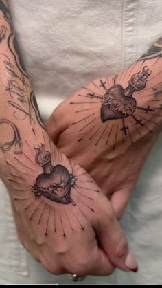 two hands with tattoos on them holding each other