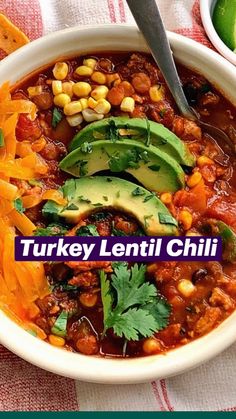 a white bowl filled with chili, corn and avocado on top of a table