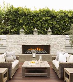 an outdoor living area with couches, tables and a fire place in the center