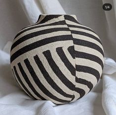 a black and white striped vase sitting on top of a bed covered in sheets or blankets