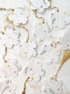 some white and gold tags with flowers on them sitting on a marble counter top,