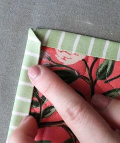 a person's hand is touching the corner of a cloth with flowers on it