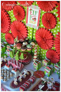 the dessert table is set up with red paper flowers and green polka dot wallpaper