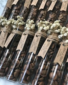 several bottles filled with nuts and flowers on top of a white marble counter topped with brown tags