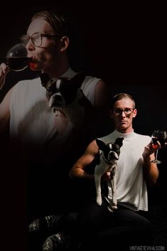 a man sitting down drinking from a wine glass while holding a small dog in his lap