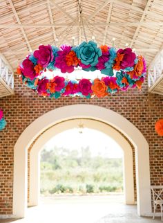 an archway decorated with paper flowers and hanging from the rafters in front of it