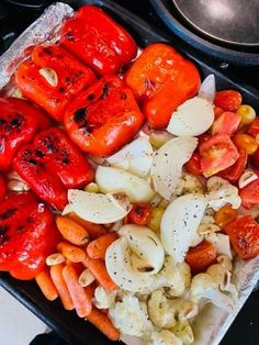 there are many different types of vegetables in the tray on the stove top, including carrots and cauliflower