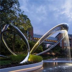 an artistic sculpture in the middle of a park with water spouting from it