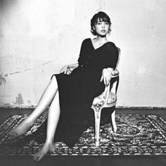 a woman sitting in a chair on top of a rug with her legs crossed out