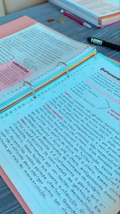 a binder with writing on it sitting next to a pen and paper clippings