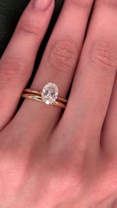 a woman's hand with two gold rings and a diamond ring on her finger