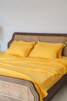 a bed with yellow sheets and pillows on it