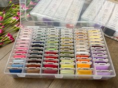 a box filled with lots of different colored spools of thread on top of a wooden table