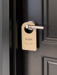 a close up of a door handle on a black door with a sign that says please