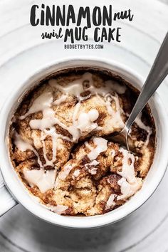 a cup filled with cinnamon rolls on top of a white plate next to a spoon