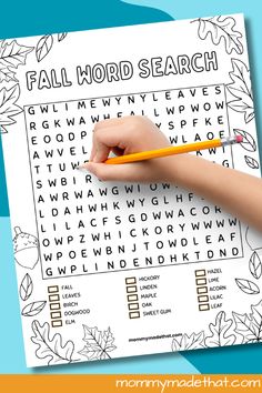 a child's hand holding a pencil and writing on a fall word search page