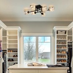 a walk in closet with lots of clothes and shoes on the shelves next to a window