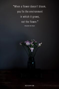 a vase filled with flowers sitting on top of a wooden table next to a wall