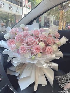 a bouquet of pink roses sitting on the dashboard of a car