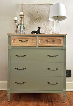 a green dresser with two drawers and a white lamp on top of it in a room