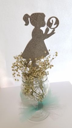 a glass vase filled with flowers and a cutout of a girl holding a lollipop