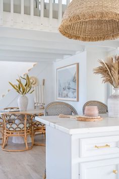 a white kitchen with an island and wicker baskets hanging from the ceiling over it