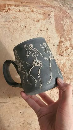 a hand holding a coffee mug with skeletons on it