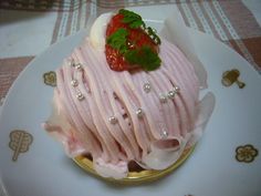 a plate topped with a strawberry covered pastry on top of a white and gold plate