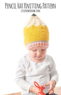 a baby wearing a knitted hat and holding scissors