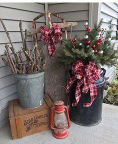 two buckets filled with christmas decorations sitting on top of a porch next to a tree