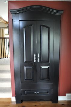 a large black door in the corner of a room with red walls and carpeting