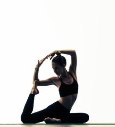 a woman doing yoga poses in front of a white wall with her hands behind her head