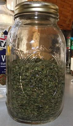 a glass jar filled with herbs on top of a counter