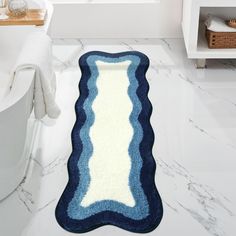 a blue and white bathroom rug in front of a bathtub with a toilet next to it