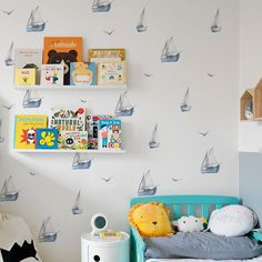 a child's bedroom decorated in white and blue with sailboats on the wall