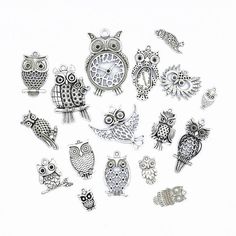 many different types of owl charms on a white surface with one clock in the middle