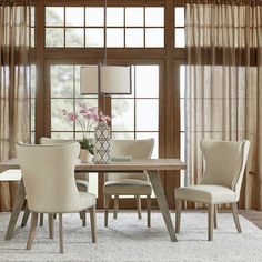 a dining room table and chairs in front of a large window with sheer drapes