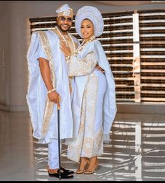 two people dressed in white and gold posing for the camera