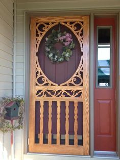 a wooden door with a wreath hanging on it's front porch next to a red door