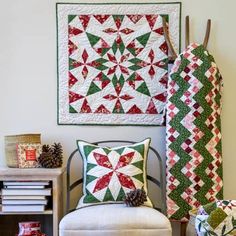 two quilts are hanging on the wall next to a chair with a pillow and blanket