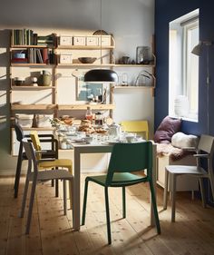 a dining room table and chairs in front of a bookshelf with shelves on the wall