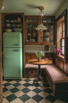 a green refrigerator sitting next to a table in a room with black and white checkered flooring