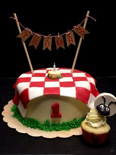 a red and white checkered table cloth cake with cupcakes on the side