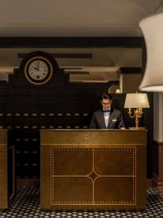 a man in a tuxedo standing at the front desk of a hotel