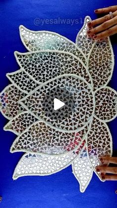 the hands are holding an intricately designed paper doily that looks like a flower