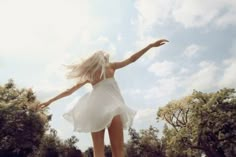 a woman in a white dress is riding a skateboard