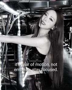 a woman with long hair standing in front of a metal pole and looking at the camera