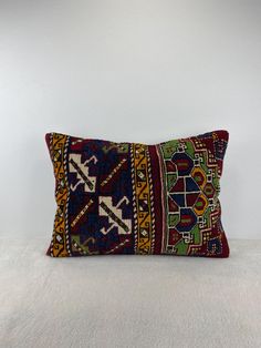 a colorful decorative pillow sitting on top of a white bed covered in blankets and pillows